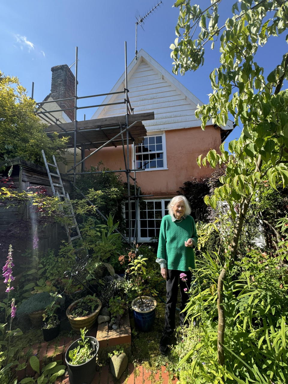 Gill Hayes-Newington in her garden which contains her neighbour's scaffolding. (SWNS)