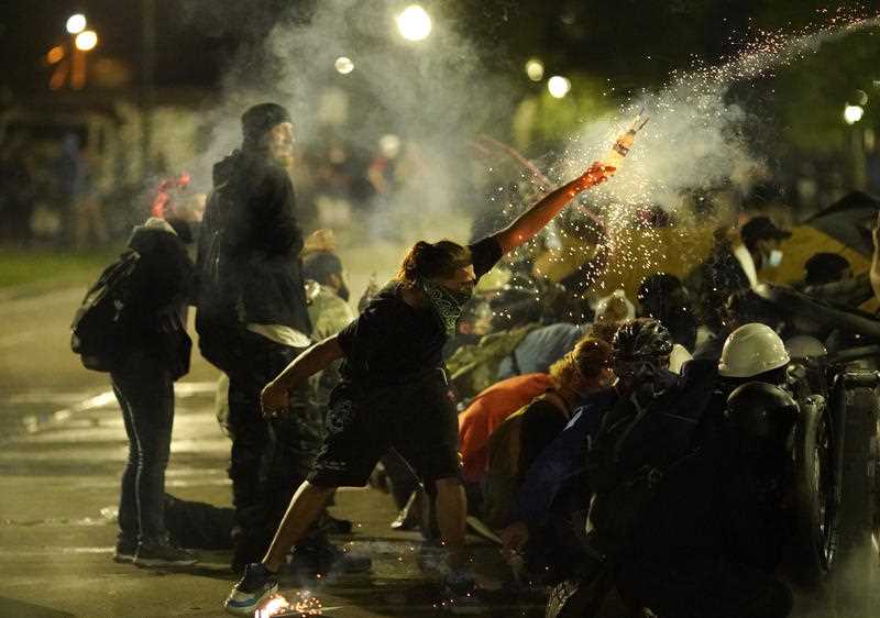 A protester launches a projectile toward police during clashes outside the Kenosha County Courthouse.