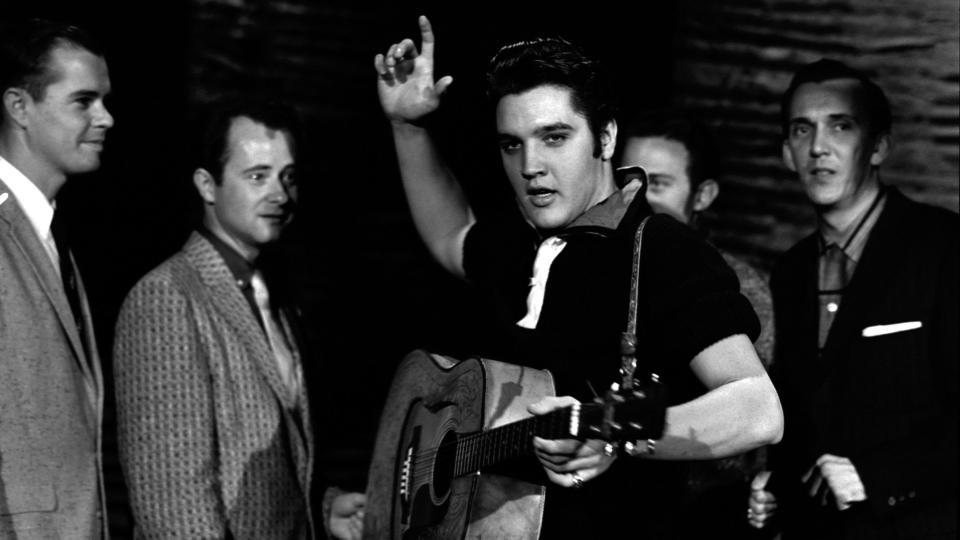 elvis presley holding his guitar while rehearsing for a performance
