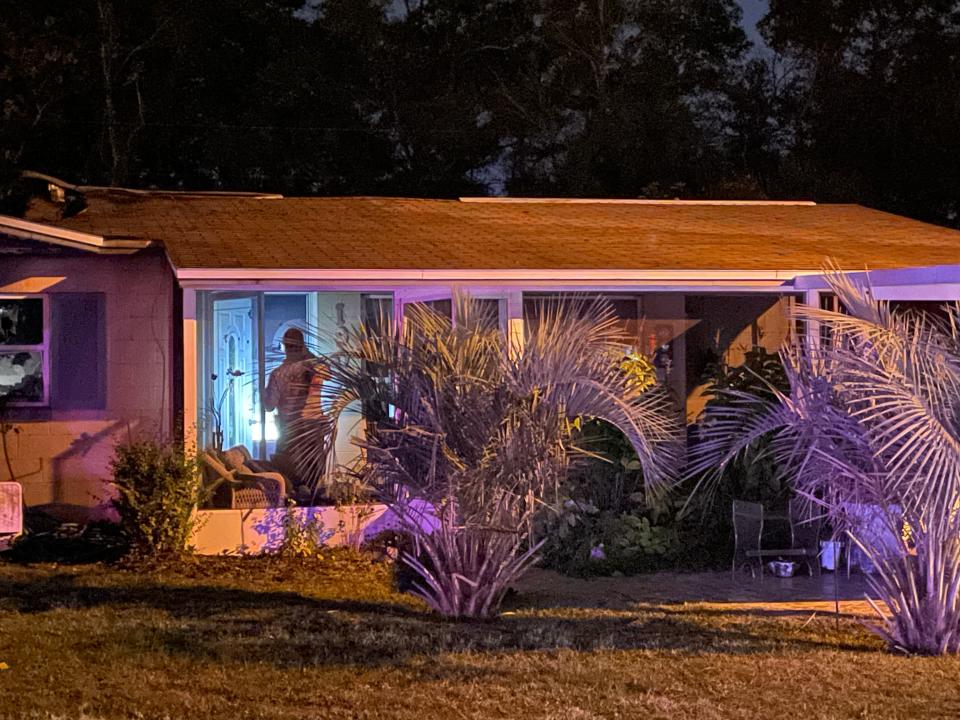 A fire official takes pictures of an Ocala home damaged by smoke and fire before entering on Friday night.