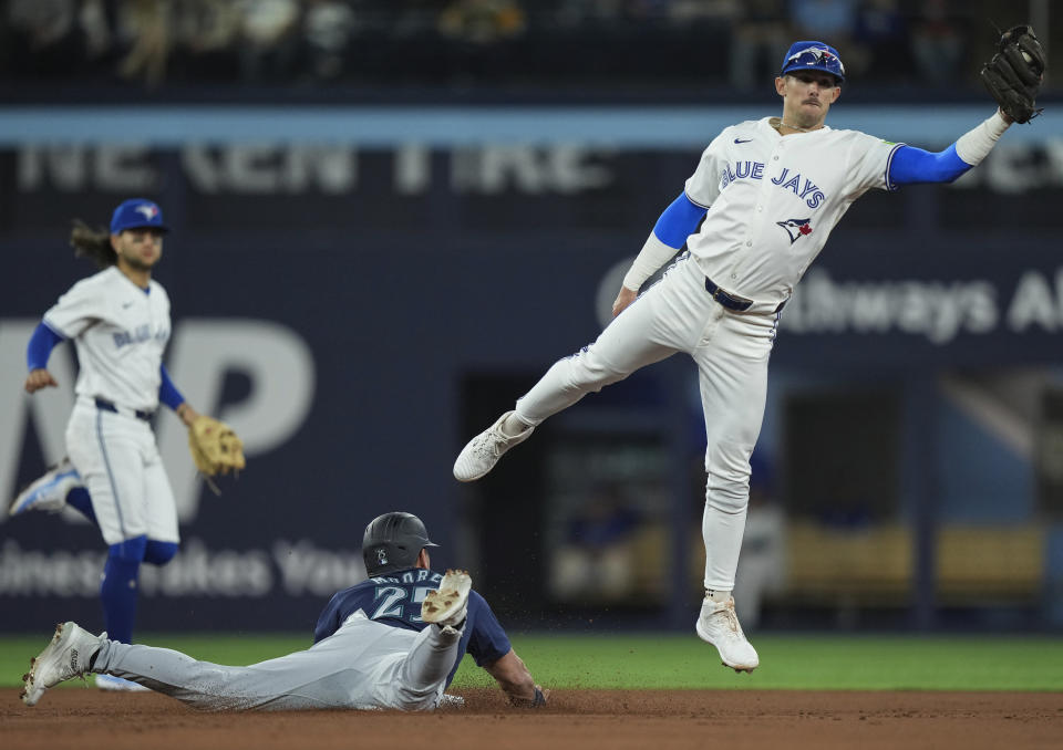 Seattle Mariners' Dylan Moore (25) steals second base as Toronto Blue Jays' Cavan Biggio (8) reaches for the throw during the third inning of a baseball game in Toronto, Wednesday, April 10, 2024. (Nathan Denette/The Canadian Press via AP)