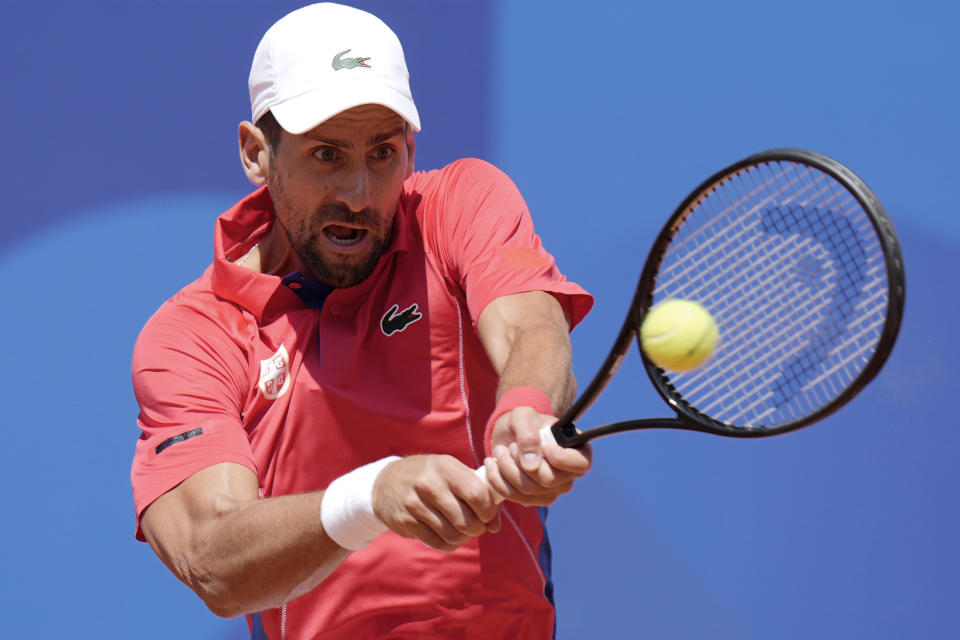 El serbio Novak Djokovic le pega con las dos manos a la pelota ante el español Rafael Nadal durante el partido de la segunda ronda del tenis de los Juegos Olímpicos en el estadio Roland Garros, el lunes 29 de julio de 2024, París, Francia. (AP Foto/Andy Wong)