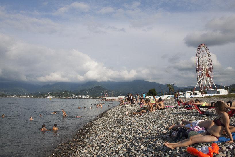 In this Aug. 1, 2012, photo, tourists swim and sunbathe in the Black Sea resort town of Batumi in Georgia. The transformation of Batumi, an ancient city of 180,000 near the border with Turkey, is a vivid example of Georgia’s drive to capitalize on its tourism potential in a bid to boost the economy in this struggling ex-Soviet nation, where nearly 1/5 of the population lives in poverty, according to conservative estimates. The government has attracted top foreign investors, such as U.S. estate magnate Donald Trump, to build hotels and develop and renovate tourist sites and aggressively marketed Georgia as tourism hot spot abroad. (AP Photo/Maria Danilova)