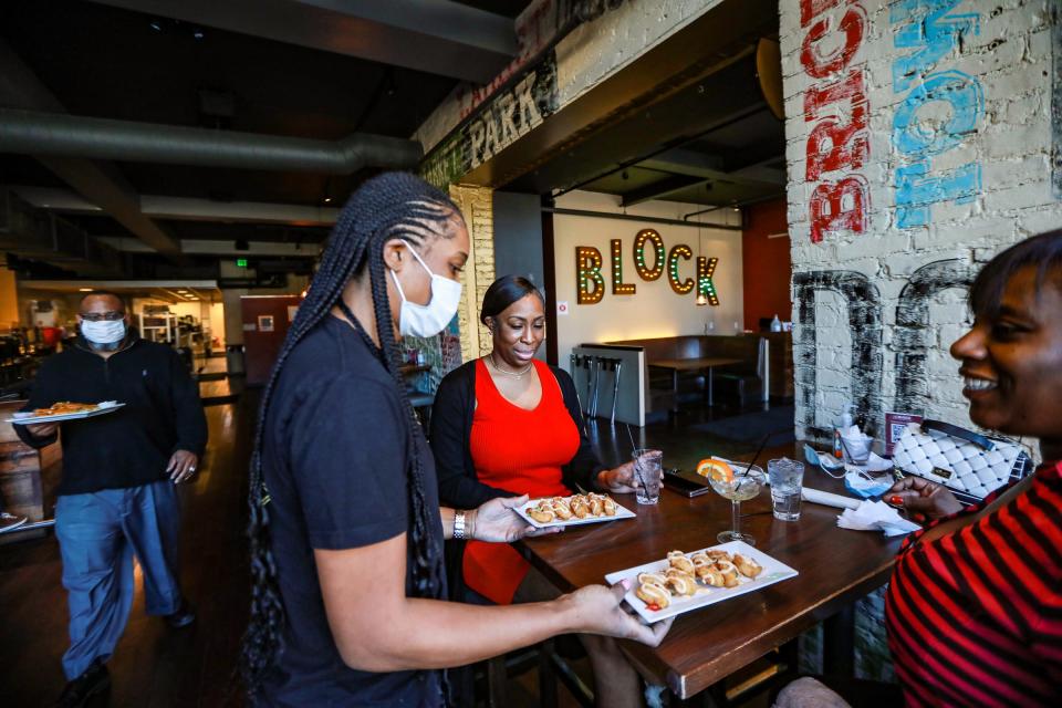 Bartender Sesaly Austin brings plates of shotgun shrimp to Taiyisha Lee and Nicole u0022Kokou0022 Rowe, with Director of Event Operations Beckwith u0022B.J.u0022 Pearson Jr. bringing the last plate of chicken quesadillas at The Block in Detroit on Feb. 25, 2021.