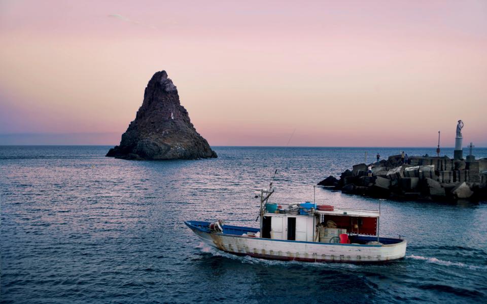 A fishing boat leaves port in search of the day's catch in the province of Catania in Sicily. - Credit: Getty Images