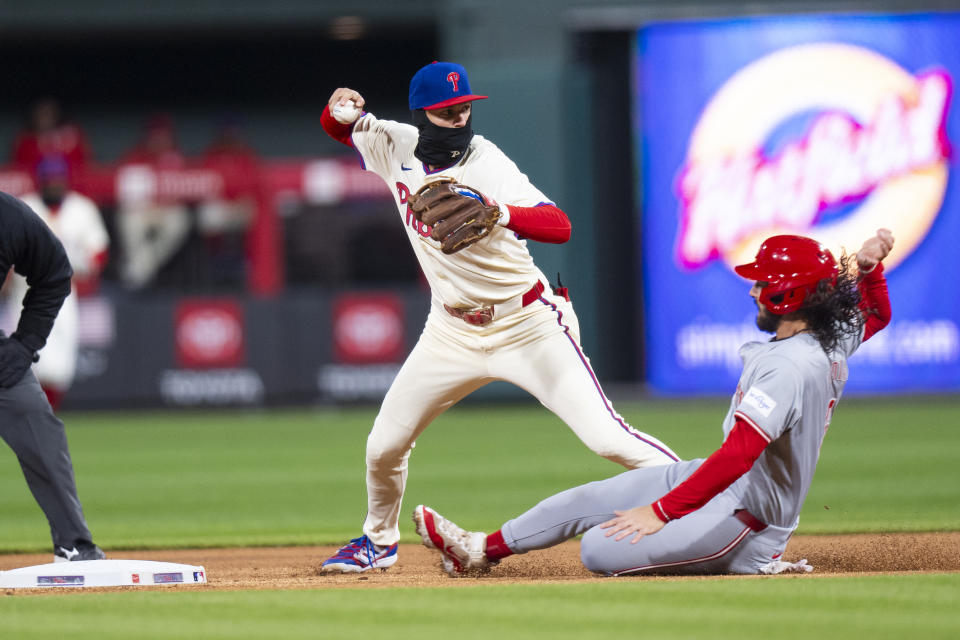 Philadelphia Phillies shortstop Trea Turner, left, gets the force out on Cincinnati Reds' Jonathan India during the first inning of a baseball game Wednesday, April 3, 2024, in Philadelphia. Christian Encarnacion-Strand was safe at first. (AP Photo/Chris Szagola)