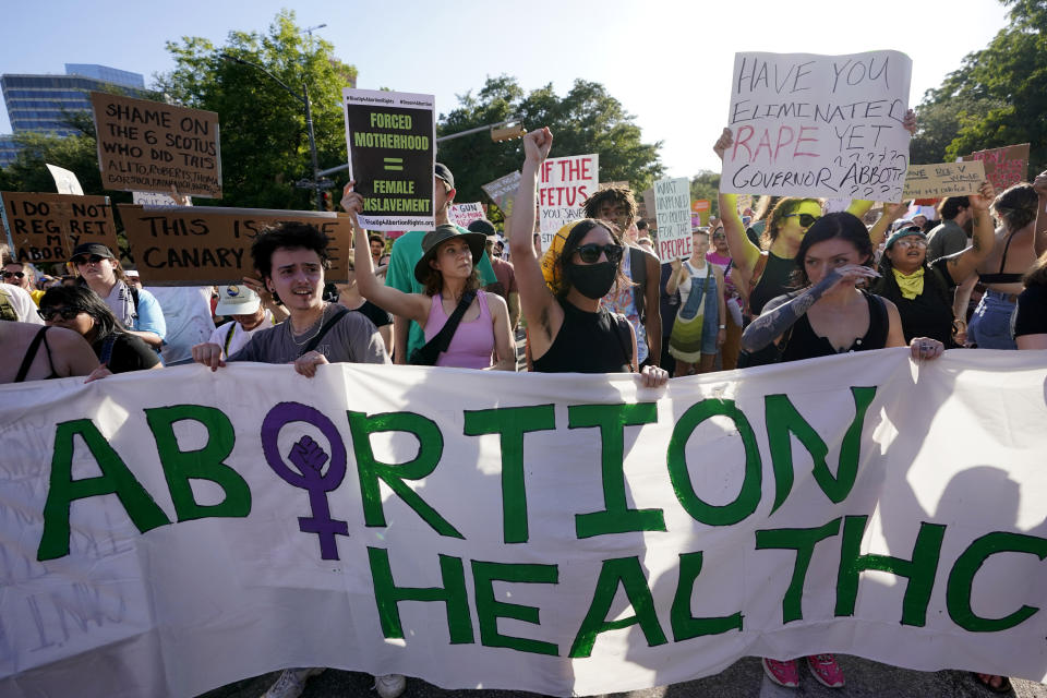 Protesters march and hold up signs, including "Forced motherhood = female enslavement"