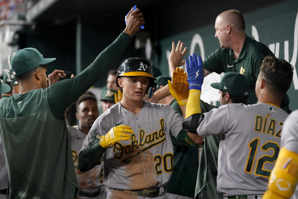 Oakland Athletics' Zack Gelof (20) celebrates in the dugout with the team after hitting a two-run home run athat also scored Tony Kemp in the seventh inning of a baseball game against the Texas Rangers, Saturday, Sept. 9, 2023, in Arlington, Texas. (AP Photo/Tony Gutierrez)
