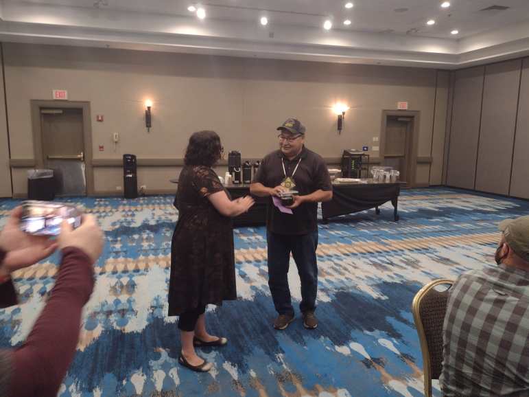 The Rev. Miranda Hassett presents a $4,000 check in a purple envelope — the color of repentance — to Ho-Chunk Nation Historic Preservation Officer Bill Quackenbush on Aug. 16, 2022. The money went to the Wisconsin Inter-Tribal Repatriation Committee, which works to repatriate artifacts to Indigenous nations and preserve historic sites, such as effigy mounds. (Frank Vaisvilas / Green Bay Press-Gazette)