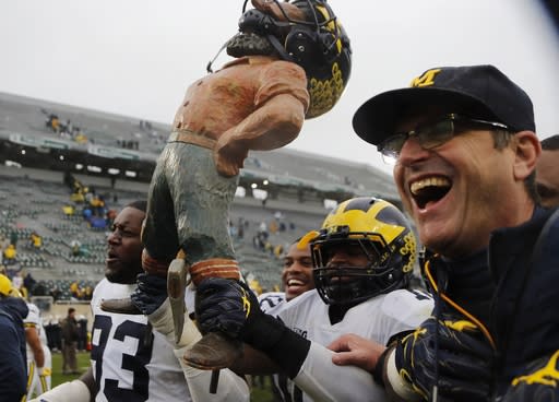 Michigan tight end Zach Gentry (83), linebacker Devin Bush, and head coach Jim Harbaugh walk off the field with the Paul Bunyan trophy after an NCAA college football game against Michigan State, Saturday, Oct. 20, 2018, in East Lansing, Mich. Michigan won 21-7. (AP Photo/Carlos Osorio)