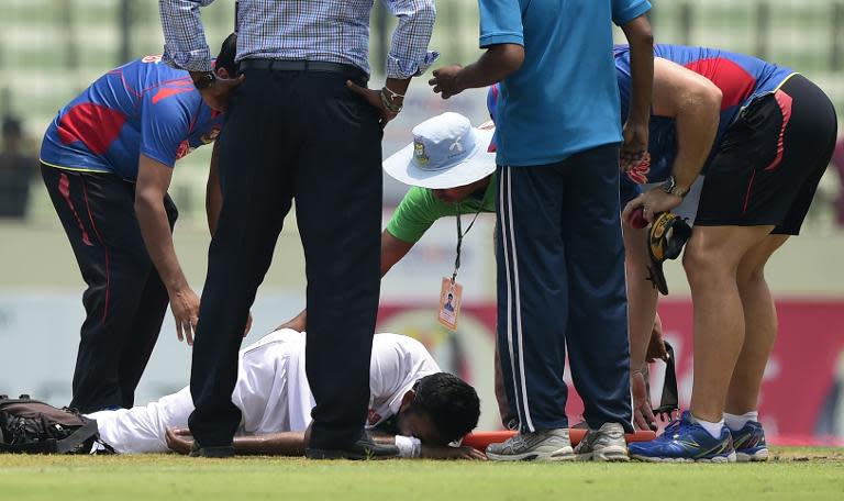 Bangladesh's Shahadat Hossain (C) is attended to by officials following an injury on the first day of the second Test against Pakistan in Dhaka on May 6, 2015