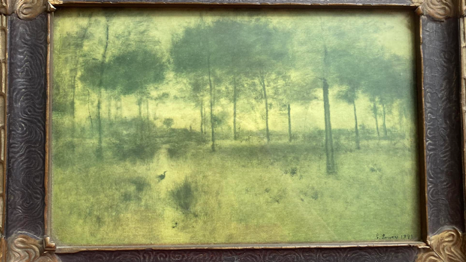 A green-tinged print of The Home of the Heron by George Inness in a frame. 