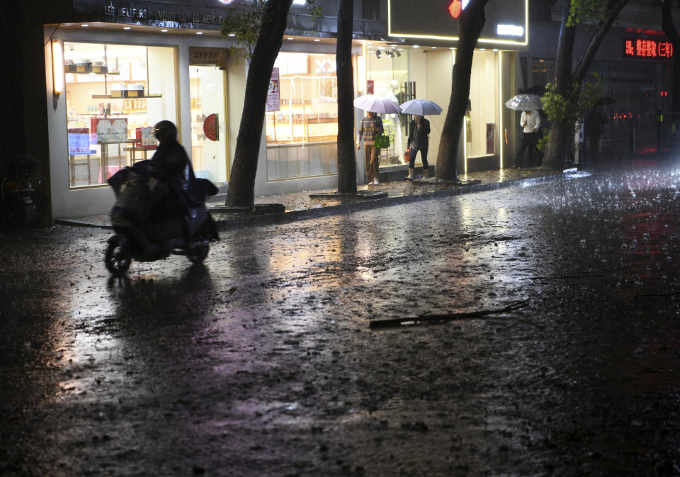 Residents pass through a rain storm in Nanchang in eastern China's Jiangxi province Tuesday, April 2, 2024. Violent rain and hailstorms have killed some people in eastern China's Jiangxi province this week, including people who fell from their apartments in a high-rise building. (Chinatopix Via AP) CHINA OUT