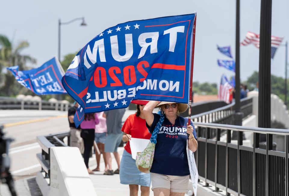 Trump supporters carry flags near Mar-a-Lago  in Palm Beach, Florida on August 9 2022.Former president Donald Trump says the FBI conducted a search of his Mar-a-Lago estate. 