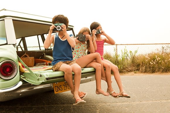 Three kids taking photos.