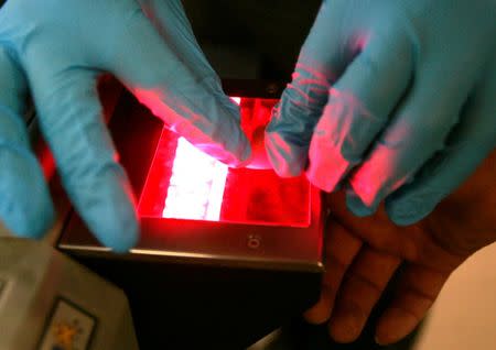 A Mexican national has his thumb fingerprint taken on a digital scanner by a U.S. Border Patrol agent after the Mexican was caught attempting an undocumented entry into the U.S. from Mexico in Laredo, Texas May 3, 2006. REUTERS/Rick Wilking