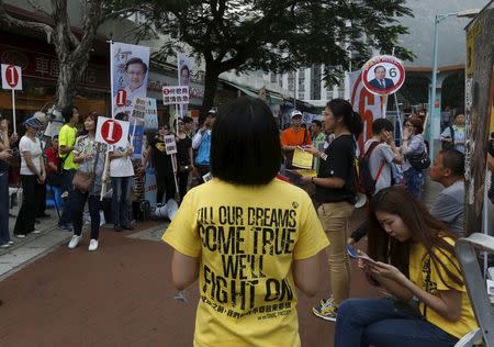 A supporter (C, in yellow) from pro-democracy group Civic Passion stands in front of supporters of other candidates during a district council election campaign rally in Hong Kong, China November 22, 2015. REUTERS/Bobby Yip