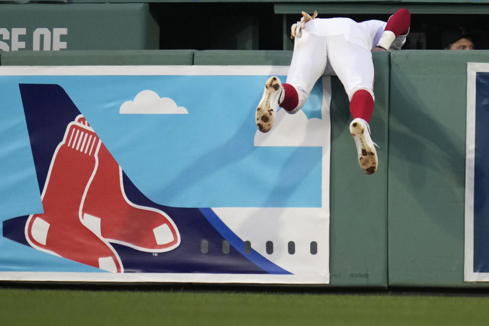 Boston Red Sox outfielder Jarren Duran (16) hangs over the bullpen wall after trying to chase down a two-run home run by Toronto Blue Jays' George Springer during the third inning of a baseball game at Fenway Park, Tuesday, June 25, 2024, in Boston. (AP Photo/Charles Krupa)