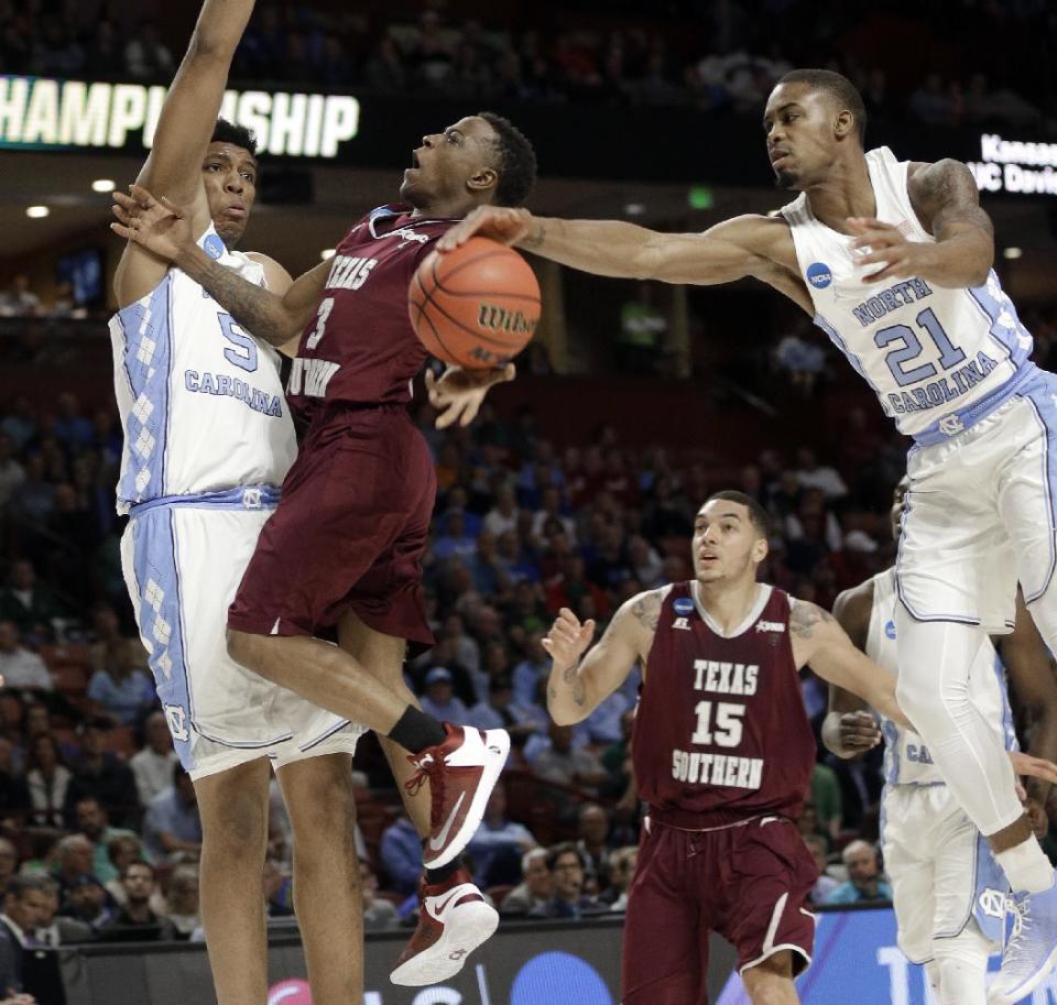 North Carolina's Seventh Woods (21) blocks a shot by Texas Southern's Demontrae Jefferson (3) as Tony Bradley (5) defends during the first half in a first-round game of the NCAA men's college basketball tournament in Greenville, S.C., Friday, March 17, 2017. (AP Photo/Chuck Burton)