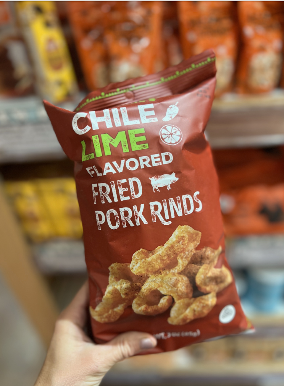 Bag of Chile Lime flavored fried pork rinds being held in a store aisle