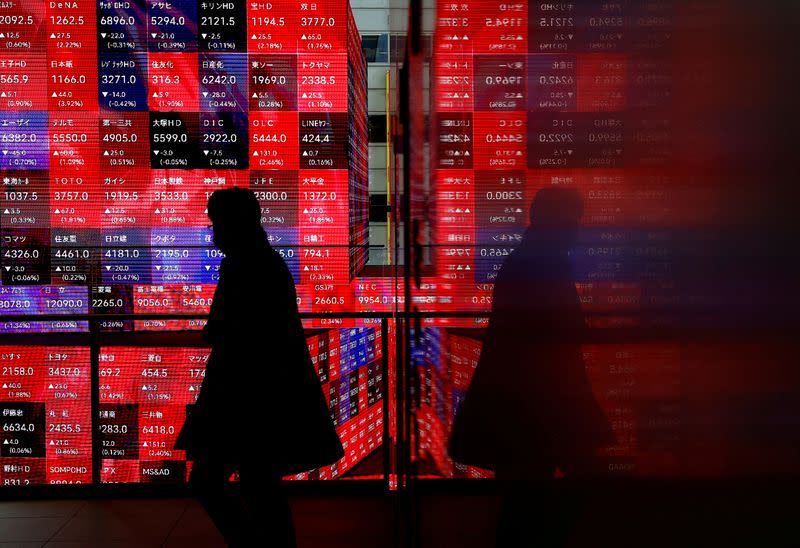 A visitor walks past Japan's Nikkei stock prices quotation board inside a building in Tokyo