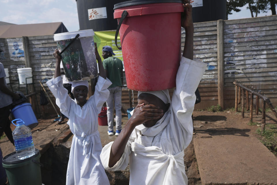 Young girls carry buckets of chlorinated water they fetched from a water point outside a clinic, in Harare, Zimbabwe, Sunday Nov. 19, 2023. A cholera outbreak in Zimbabwe is suspected of killing more than 150 people and infecting more than 8,000. The virulent bacterial disease is striking fear in many in the southern African country who live in impoverished and neglected areas where sanitation conditions are poor and local government failures have left them with no access to clean water. (AP Photo/Tsvangirayi Mukwazhi)