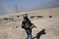 An Iraqi federal police member walks towards the frontline outside the town of Hamam al-Alil, Iraq, Sunday, Feb. 2017. The battle for the western half of Mosul city, which began Sunday, is expected to be prolonged and difficult due to a densely packed civilian population and older, narrower streets.(AP Photo/Bram Janssen)