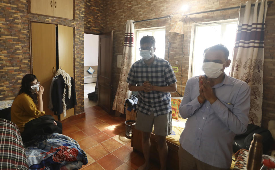 A family, wearing face masks as a precaution from coronavirus, prays inside their house on the first day of Navratri festival, where Hindu fast for nine days, in New Delhi, India, Wednesday, March 25, 2020. The world's largest democracy went under the world's biggest lockdown Wednesday, with India's 1.3 billion people ordered to stay home in a bid to stop the coronavirus pandemic from spreading and overwhelming its fragile health care system as it has done elsewhere. For most people, the new coronavirus causes mild or moderate symptoms, such as fever and cough that clear up in two to three weeks. For some, especially older adults and people with existing health problems, it can cause more severe illness, including pneumonia and death. (AP Photo/Manish Swarup)