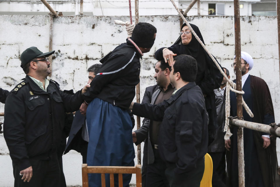 This picture provided by ISNA, an semi-official news agency, taken on Tuesday, April 15, 2014 shows Samereh Alinejad, right, slapping blindfolded Bilal, who was convicted of murdering her son Abdollah prior to his execution in public in the northern city of Nour, Iran. Bilal who was convicted of killing Abdollah Hosseinzadeh, was pardoned by the victim's family moments before being executed. (AP Photo/ISNA, Arash Khamoushi)