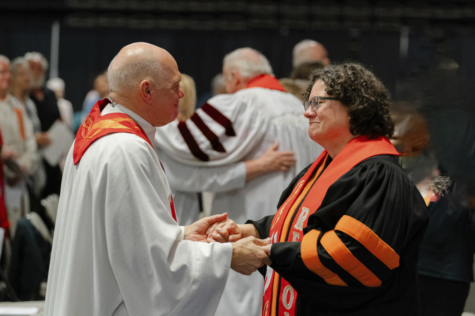 In this photo provided by the United Methodists of Eastern Pennsylvania, Rev. Dr. Beth Stroud, right, holds hands with Bishop John Schol after offering a prayer of blessing at the Wildwoods Convention Center, Wildwood, N.J., on Tuesday, May 21, 2024, as he prepares to retire in August. Twenty years ago, Stroud was defrocked as a pastor after telling her congregation that she was in a committed same-sex relationship. On Tuesday night, less than three weeks after the UMC repealed its anti-LGBTQ bans, she was reinstated. (Shari DeAngelo/United Methodists of Eastern Pennsylvania via AP)