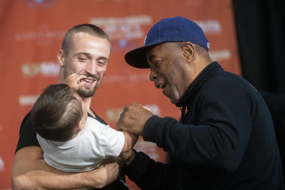 Boxer Ivana Habazin's trainer Bashir Ali, right, smiles as he jokingly boxes with a baby during a weigh in Friday, Oct. 4, 2019, in Flint, Mich. Ali was later punched by a man and fell to the ground bloodied. He was sent to McLaren Hospital in Flint to be treated. Habazin and Claressa Shields are scheduled to fight Saturday for the WBO and WBC super welterweight championships. (Jake May/The Flint Journal via AP)