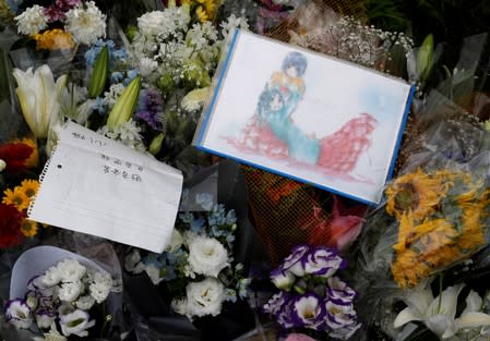 Flowers and a drawing with anime characters dedicated to the victims of the fire are seen left outside the Kyoto Animation building which was torched by arson attack, in Kyoto