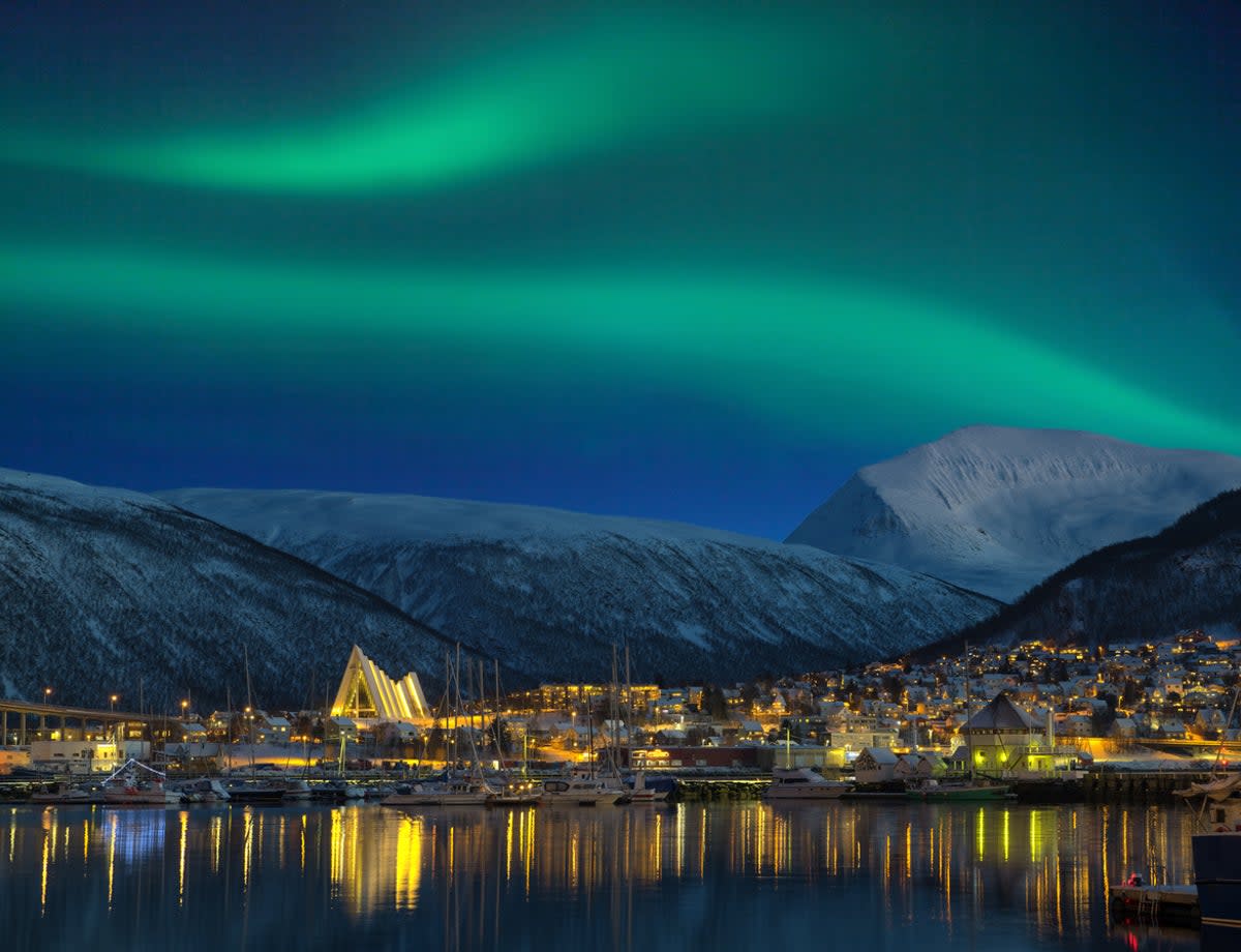 A view of an illuminated Tromso with the Northern Lights over the city (Getty Images)