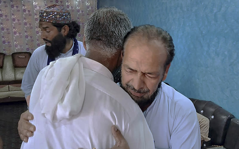 People hug a man whose son is missing after a shipwreck off the Greek coast.