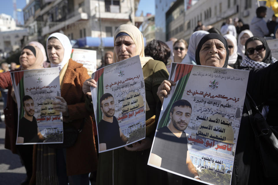 Palestinians hold posters of Palestinian prisoner Nasser Abu Hamid during a protest, Tuesday, Dec. 20, 2022, in the West Bank city of Ramallah, after he died of lung cancer in Israel. Abu Hamid was a former leader of the Al Aqsa Martyrs' Brigade, the armed wing of Palestinian President Mahmoud Abbas's Fatah party. He had been serving seven life sentences after being convicted in 2002 for involvement in the deaths of seven Israelis during the second Palestinian intifada, or uprising, against Israel's occupation in the early 2000s. (AP Photo/Majdi Mohammed)