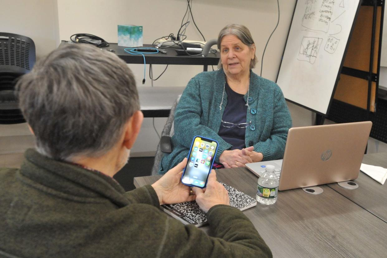 Grace Buscher of GMB Systems in Squantum, right, explains to a senior at the Milton Council on Aging how scammers target seniors through texts, emails, and phone calls. Friday, Feb. 16, 2024.