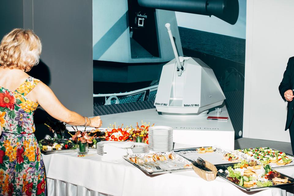 Model of a Swedish Bofors 57 Mk3 naval gun behind a table full of food at defense fair
