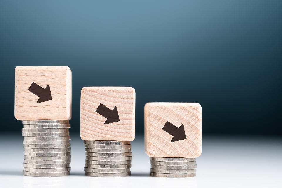 Image of three stacks of coins with blocks atop with downward arrows