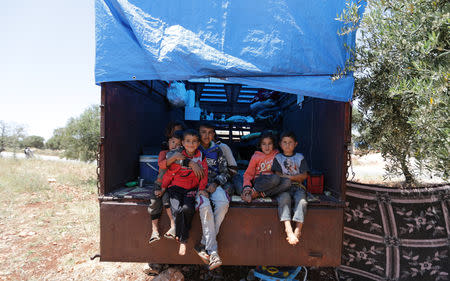 FILE PHOTO: Children sit on the back of a truck in an olive grove at the town of Atmeh, Idlib province, Syria May 19, 2019. REUTERS/Khalil Ashawi