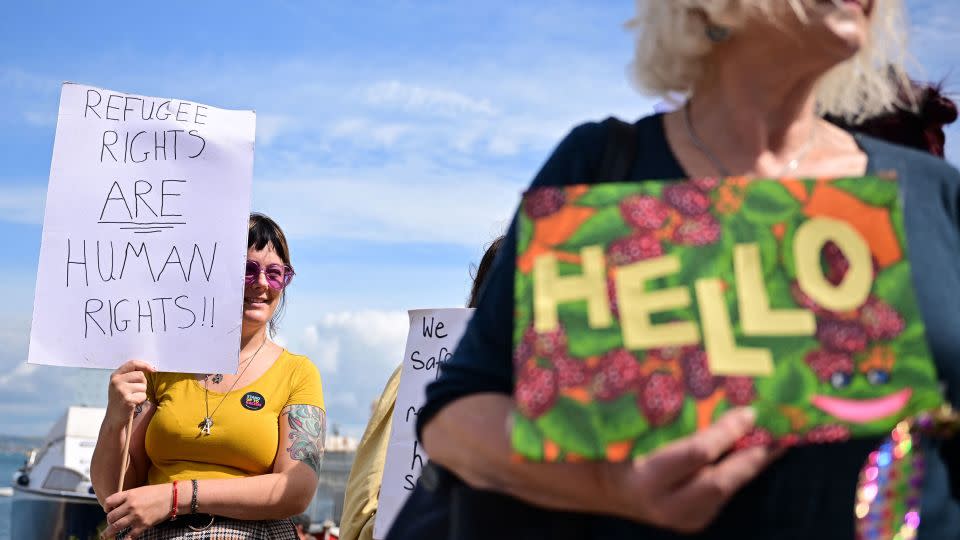 People hold up placards to welcome migrants ahead of their expected arrival at the Bibby Stockholm accommodation barge in southwest England on August 7, 2023.  - Ben Stansall/AFP via Getty Images