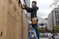 Ahead of the presidential election, a worker boards up a Pret A Manger restaurant along K Street NW, Friday, Oct. 30, 2020, in downtown Washington not far from the White House. (AP Photo/Jacquelyn Martin)