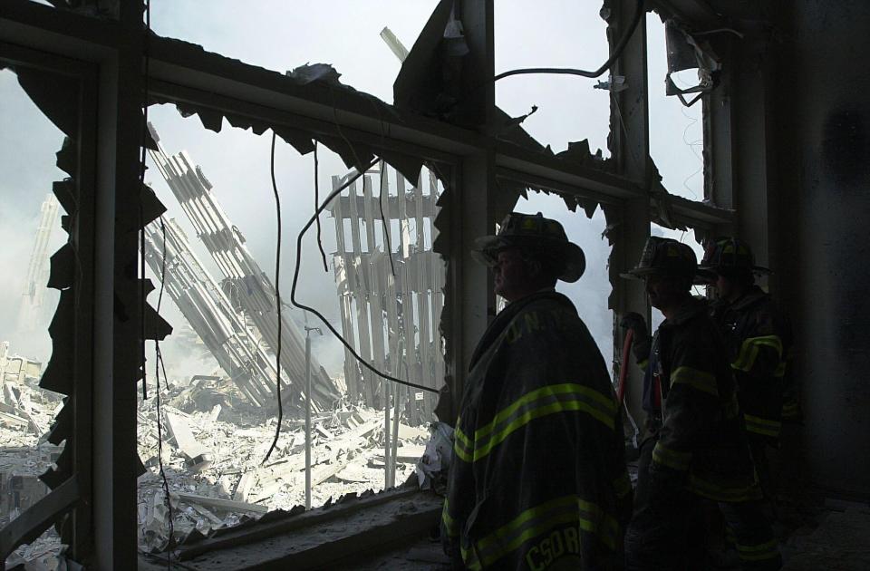 New York City Firefighters look at the remains of the World Trade Center on Sept. 11, 2001. Two hijack airliners crashed against the twin towers which subsequently collapse killing both the trapped and the rescuers. 