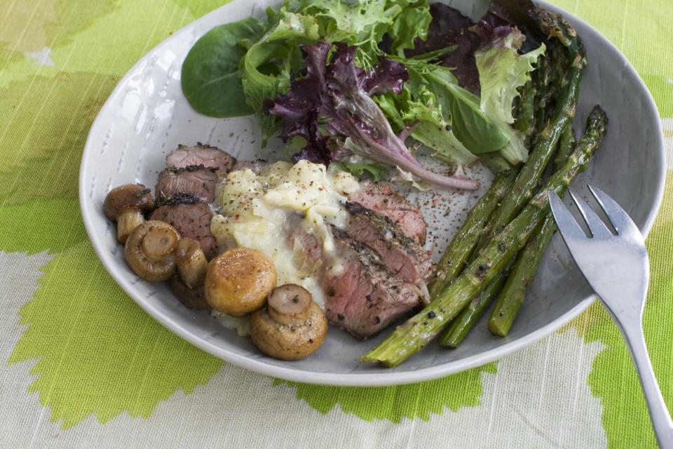 In this image taken on March 11, 2013, grilled lamb steaks with artichoke lemon sauce are shown served on a plate in Concord, N.H. (AP Photo/Matthew Mead)