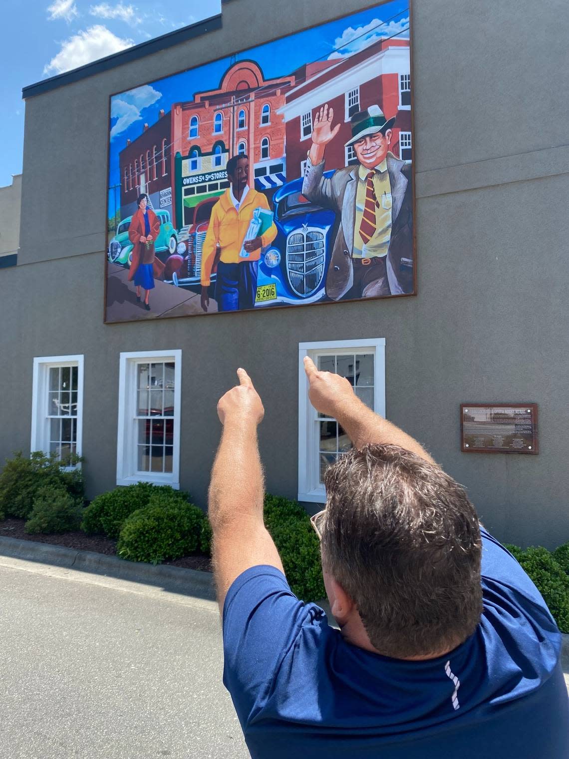 Will Hinton points out details of the mural he and a Louisburg college student painted based on a downtown scene in a silent movie from 1936.