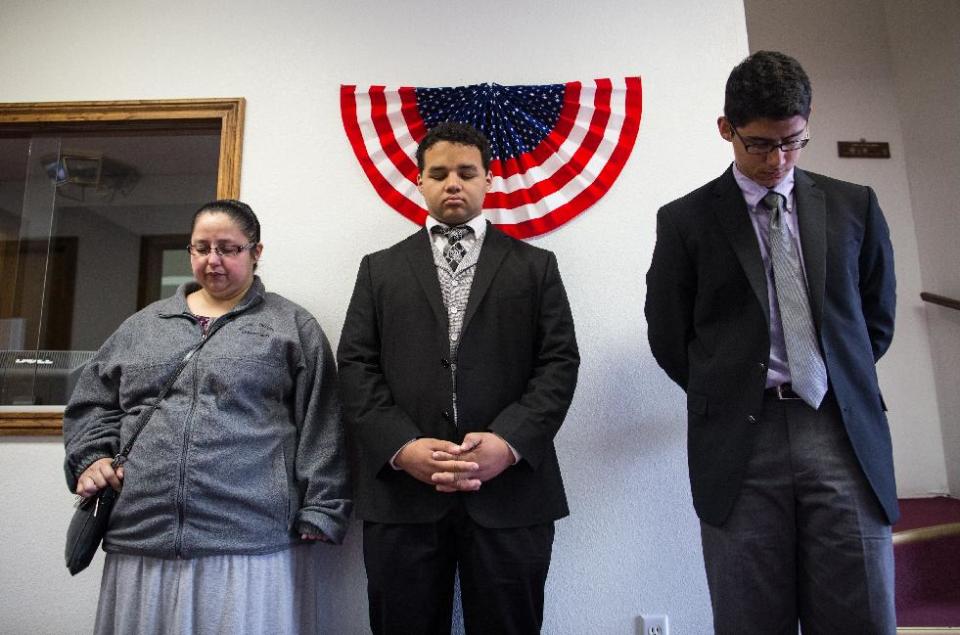 Rebecca Gutierrez, Marcus Bates and Daniel Ramirez pray for the victims and families affected by the Fort Hood shooting during a memorial service at the Tabernacle Baptist Church on Sunday, April 6, 2014, in Killeen, Texas. On April 2, 2014, three people were killed and 16 were wounded when a gunman opened fire before taking his own life at the Fort Hood military base. (AP Photo/ Tamir Kalifa)