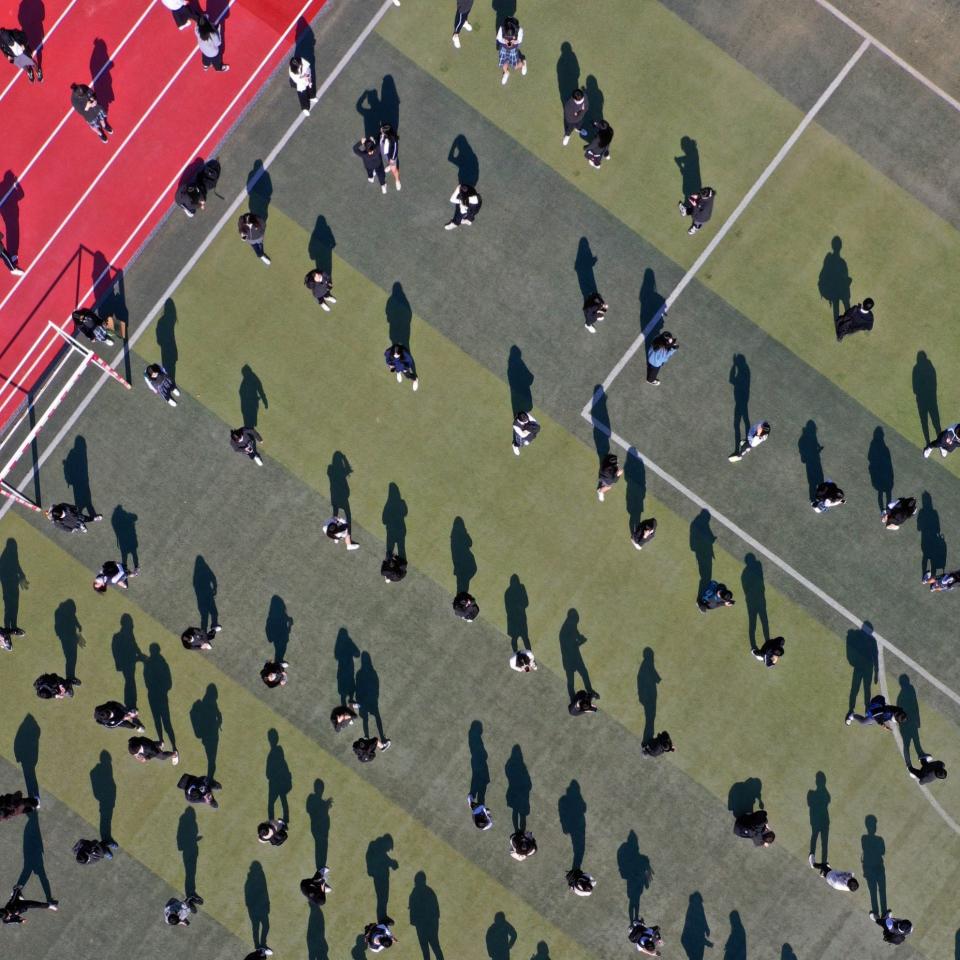 Students maintain social distance as they wait to undergo swab tests for COVID-19 after one student tested positive for the coronavirus at a high school in Daegu - YONHAP/EPA-EFE/Shutterstock 