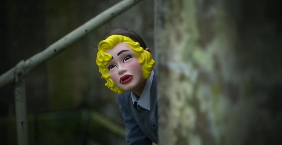 A young man wearing a woman's face mask in "Men"