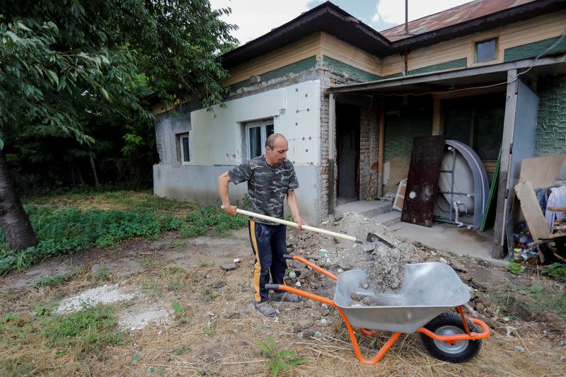 Alberto Gogu uses a shovel to clear debris in his courtyard