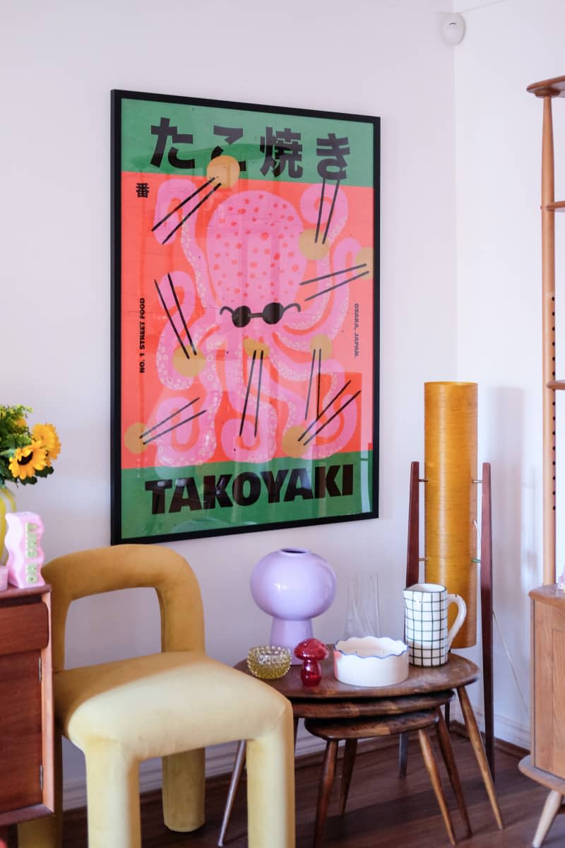 Nesting wood tables and graphic poster seen in corner of white living room.