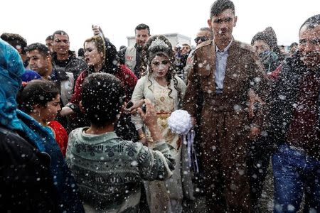 Iraqi newlyweds, who fled Mosul, Hussain Zeeno Zannun (R) 26, and Chahad, 16, are showered in foam during their wedding party at Khazer camp in Iraq February 16, 2017. REUTERS/Zohra Bensemra